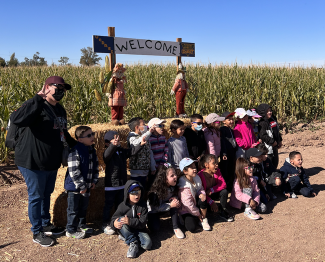 A teacher and her students pose in front of the corn maze located at the Desert Research and Extension Center.