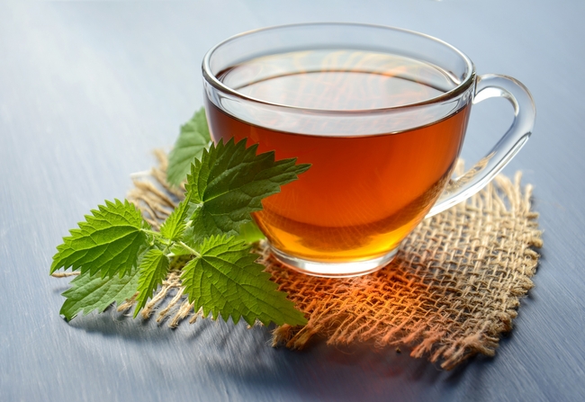 A cup of herb tea on a burlap coaster.