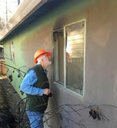 Steve Quarles, UC Cooperative Extension advisor emeritus, looks at a garage attached to an older house in Paradise where the radiant heat from a nearby fence and line of planted vegetation ignited and were sufficiently hot enough to break the single pane glass. Photo by Yana Valachovic