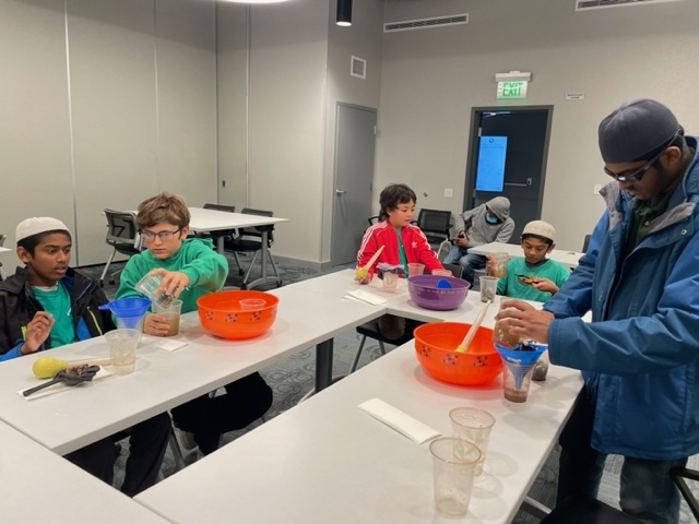 Young students team up to figure out how to make a water filter using basic materials such as a funnel, turkey baster, and cups.