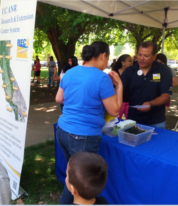 Rodolfo Cisneros sharing information about Kearney with a local resident at the 2014 Parlier Earth Day.