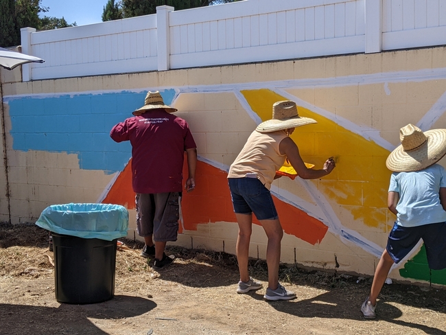 Community members painted the first layer of a colorful mural on a wall bordering the edible garden in an Eastside neighborhood