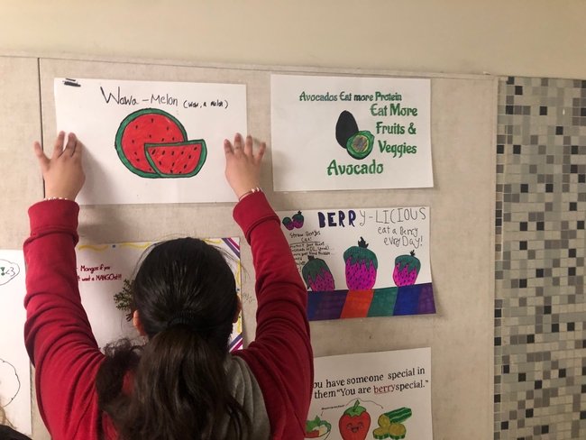 Hillview student adds her poster to the wall in one of the school's main hallways.