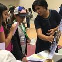 During the career fair, an Engineer speaks with youth about what she does for her job