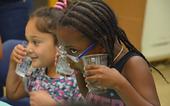 Young scientists using the sense of hearing to listen to soda bubbles during a Kitchen Science YES Project lesson.