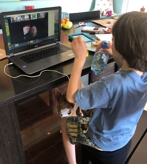 Youth drinks a bottle of water while sitting in front of a laptop. On the laptop is the Zoom application showing the video of a 4-H Advisor.
