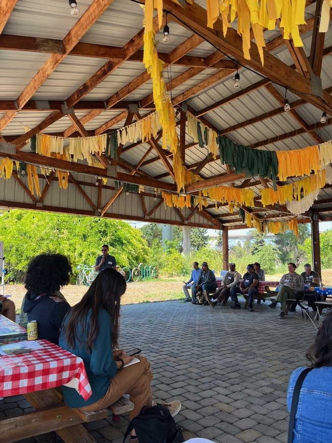 Farmers gather under a pavilion festooned with streamers