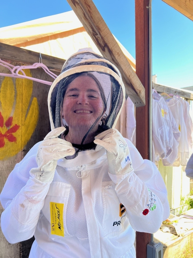 Smiling woman wears a white bee suit