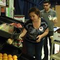 La consejera de UCCE Terri Spezzano (centro) y el educador de nutrición Javier Miramontes surten el “mercado de granjeros” con frutas y verduras frescas.