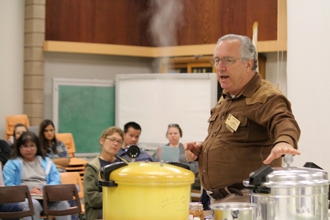 El voluntario Dennis Prendergast enseña una clase de Envasadores Maestros de  Alimentos sobre envasado a presión.