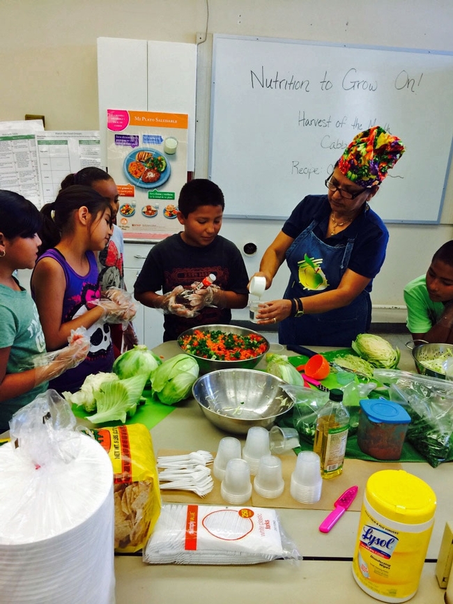 Grilda Gómez, educadora de nutrición de la UC, prepara una ensalada junto con estudiantes de la primaria Pixley.