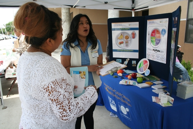 Consuelo Cid, educadora de nutrición de UC CalFresh, derecha, ayuda a una madre a registrarse en las clases de nutrición.