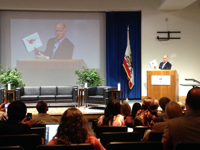 Gov. Brown holds a map showing temperature increases at climate change conference.