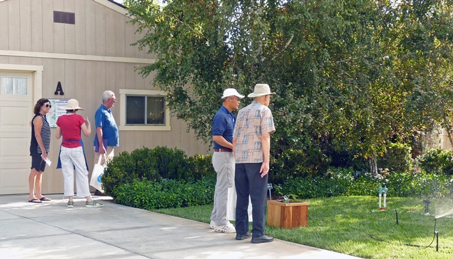 Visitors observe a demonstration of different types of sprinkler heads and drip irrigation.