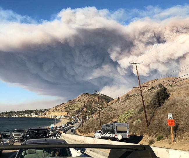 Traffic is backed up on Pacific Coast Highway as residents evacuate Malibu as a smoke plume from the Woolsey Fire rises in the background. (Photo: Wikimedia Commons)