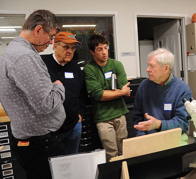 In this 2017 archived photo, Jerry Powell (seated at microscope) talks to colleagues at a Lepidopterist Society meeting at the Bohart Museum of Entomology. From left are entomologist Max Klepikov of Berkeley; UC Davis distinguished professor Don Strong of the  Department of Evolution and Ecology; and Eric Lopresti, then a UC Davis graduate student. (Photo by Kathy Keatley Garvey)