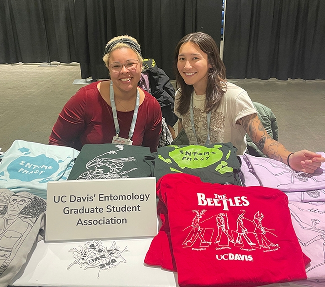 UC Davis doctoral students Iris Quayle (left) of the Jason Bond lab and Mia Lippey of the labs of UC Davis distinguished professor Jay Rosenheim and assistant professor Emily Meineke, show some of the EGSA T-shirts. Lippey serves as EGSA president, and Quayle as treasurer.