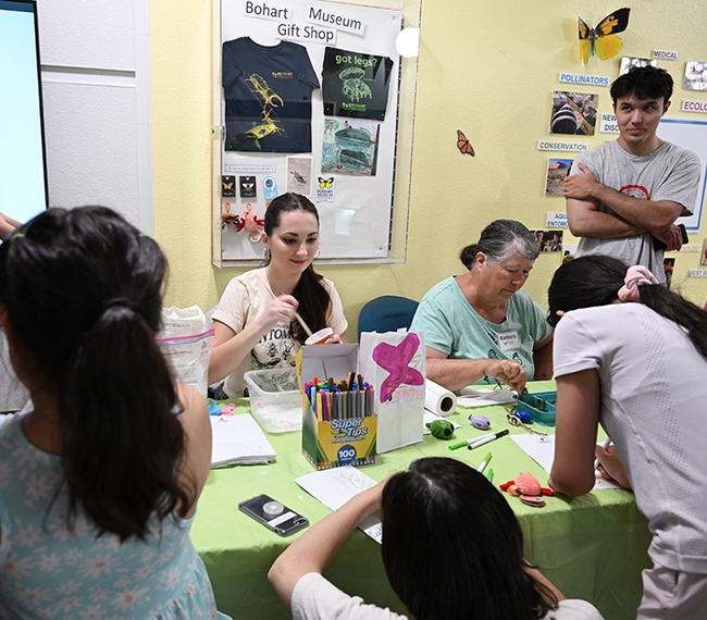 UC Davis graduate student (forensics) Riley Hoffman and fellow Bohart volunteer Barbara Heinsch lead a family arts and crafts activity.  (Photo by Kathy Keatley Garvey)