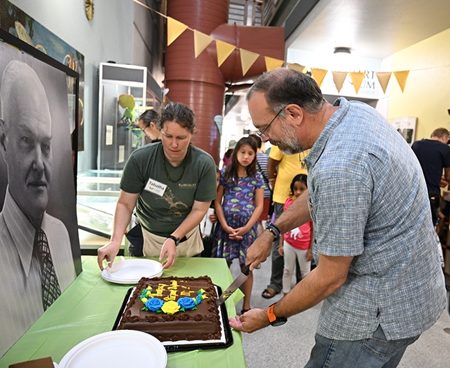 Bohart Museum director Professor Jason Bond cuts the cake while Tabatha Yang, education and outreach coordinator serves. (Photo by Kathy Keatley Garvey)