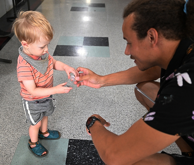 Eighteen-month-old Owen Nguyen of Davis checks out a vial holding a bug. At right is UC Davis doctoral candidate Christofer Brothers. (Photo by Kathy Keatley Garvey)