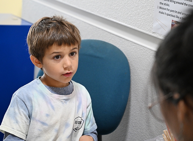 Isaiah Sahakian Frenz, 6, of Davis, listens closely to the instructions on how to make a spider web. (Photo by Kathy Keatley Garvey)