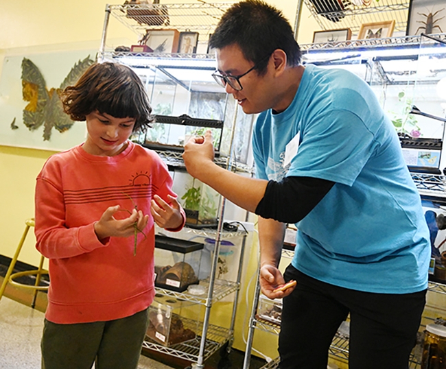 UC Davis entomology major Kaitai Liu chats with budding entomologist Eden Jett of Berkeley as she holds a walking stick. (Photo by Kathy Keatley Garvey)