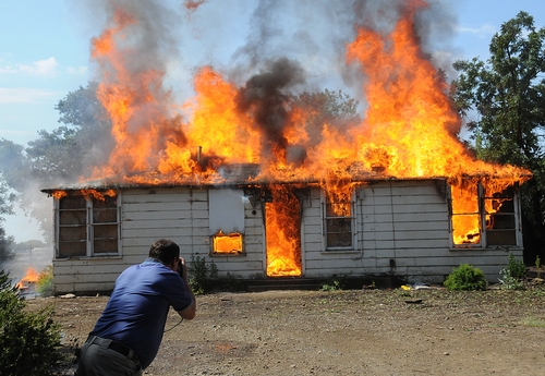 ENGULFED IN FLAMES, the Baxter House burns rapidly to the ground Tuesday in a control burn. That's UC Davis police detective Paul Henoch capturing an image of the flaming building. (Photo by Kathy Keatley Garvey)