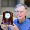 Extension apiculturist (emeritus) Eric Mussen with his engraved clock from the Almond Board of California. (Photo by Kathy Keatley Garvey)