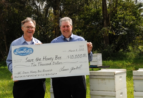 HELPING TO SAVE the honey bees is Gimbal's Fine Candies, which is donating 5 percent of the proceeds from its Honey Lovers' fruit chews to UC Davis research. Accepting the first check, issued March 8, is Extension apiculturist Eric Mussen (left) from Lance Gimbal, CEO of Gimbal's. (Photo by Kathy Keatley Garvey)