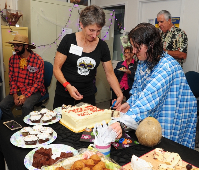 Lynn Kimsey (center), director of the Bohart, cuts the anniversary cake, as Tabatha Yang, public education and outreach coordinator disguised as a wet blanket, assists. (Photo by Kathy Keatley Garvey)