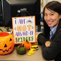 Louisa Lo, executive administrative assistant for Bruce Hammock, distinguished professor of entomology, sits next a sign proclaiming she is not afraid of spiders. She is. (Photo by Kathy Keatley Garvey)