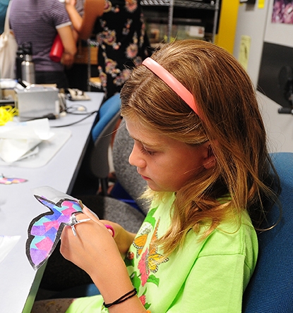 Natalie Seybold, 8, of Davis, creates a moth decoration as part of the family arts and crafts activity. (Photo by Kathy Keatley Garvey)
