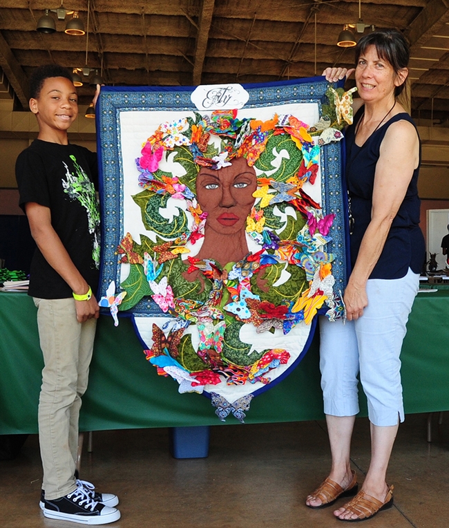 Front: Gloria Gonzalez, superintendent of McCormack Hall, Solano County Fair, and her assistant Ian Mayhew, 12, of American Canyon, display the front of LaQuita Tummings' quilt. (Photo by Kathy Keatley Garvey)