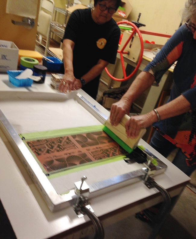 Demonstrating the silkscreen process are Gale Okumura (back) and Diane Ullman, partially seen.