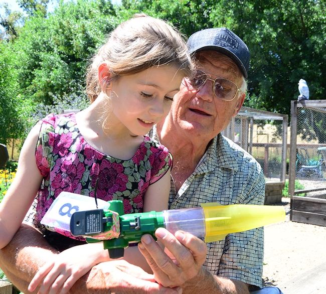 Adelaide Grandia and her grandfather, Dwight Grandia of Gulf Shores, Ala., confer on a bee vacuum device. He is teaching her how to keep bees and recently set up a hive for her. (Photo by Kathy Keatley Garvey)
