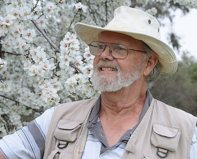 Robbin Thorp, a familiar figure in the spring, wearing his vest and trademark hat, and standing in front of a blossoming almond tree on Bee Biology Road, UC Davis. (Photo by Kathy Keatley Garvey)