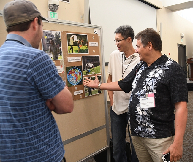 Researcher Christophe Morisseau (right) of the Hammock lab shows photos of previous water balloon battles to two colleagues. In the center is Kin Sing Stephen Lee of Michigan State University, an alumnus of the Hammock lab, and Bruce Graham Hammock (son of Distinguished Professor Bruce Dupree Hammock) of the UC Davis School of Veterinary Medicine. (Photo by Kathy Keatley Garvey)