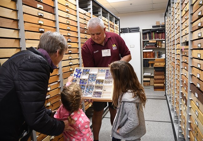 Entomologist Jeff Smith, who curates the Lepidoptera section of the Bohart Museum, shows some specimens to Vacaville residents Ginny Miller and her grandchildren, Savanna, 7, and Olivia, 4. (Photo by Kathy Keatley Garvey)