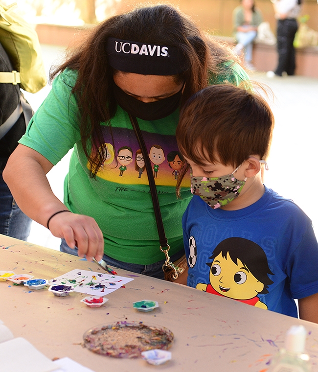 UC Davis alumnus Angie Velazquez of Los Angeles assists her son, Hudson Carr, 4, in his first Maggot Art project. (Photo by Kathy Keatley Garvey)