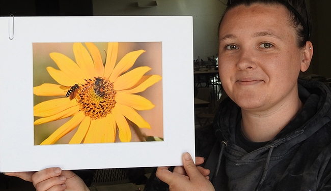 Marine biologist Leta Myers, who clerked at the Dixon May Fair judging, holds a photo by Vaca Valley 4-H'er Matthew Agbayani. It depicts a honey bee and a syrphid fly on a sunflower. (Photo by Kathy Keatley Garvey)