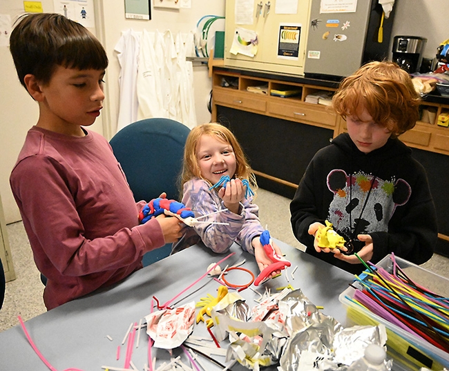 Siblings Camryn Baker, 9, Charlotte Baker, 6 and Thomas Baker, 8, all of Davis, finish their clay-modeling projects. (Photo by Kathy Keatley Garvey)