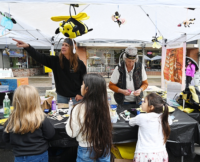CAMBP master beekeeper Sara Cutrignelli of San Martin explains bee behavior to youngsters at the arts and crafts booth, while fellow CAMBP member Paula Brackett, an apprentice level beekeeper, helps  youngsters with their creative ideas. (Photo by Kathy Keatley Garvey)