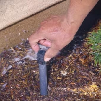 A hand turning the adjuster on an operating flood bubbler