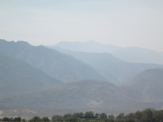 Rugged, mountainous terrain blanketed in a smoky haze.