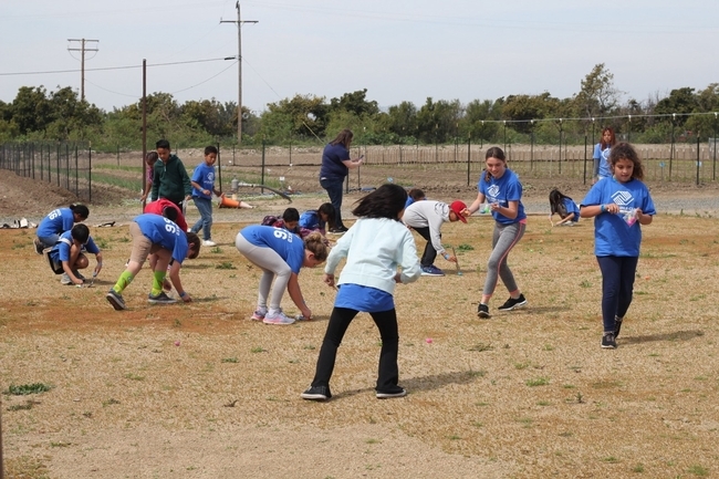 Miembros de BGCGG intentan recoger alimentos usando diferentes instrumentos durante una actividad sobre adaptación animal.