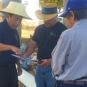 Michael Yang, UC Agriculture and Natural Resources, and Antonio Piña, AgriValley, meet with a Hmong farmer to plan a new irrigation system. Photo by Ruth Dahlquist-Willard.