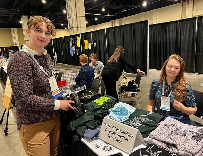 UC Davis graduate student and honey bee researcher Eliza Litsey (seated), staffing the Entomology Graduate Student Association's T-shirt table, chats with entomology student Tabby Vincentsen of the University of Florida. (Photo courtesy of Jenella Loye)