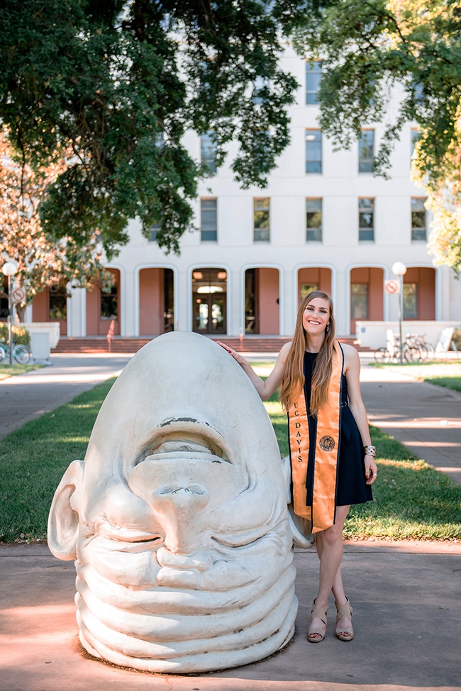 Jessica Macaluso stands next to Robert Arneson's egghead sculpture at Mrak Hall, UC Davis. She is scheduled to  receive her bachelor's degree in the fall of 2020 in psychology with a biological emphasis.