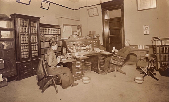 In this 1915 image, Judge William Thomas Hammock of Little Rock, Ark., sits at his desk while his daughter, Maude Hammock, works the 