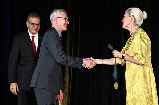 UC Davis distinguished professor Walter Leal, inducted as a Fellow of the National Academy of Inventors, receives congratulations from the NAI's Elizabeth Lea Dougherty, J.D.,  director of Inventor Education, Outreach, and Recognition in the Office of Innovation Development at the U.S. Patent and Trademark Office. At left is NAI president Paul Sanberg. (Courtesy Photo)